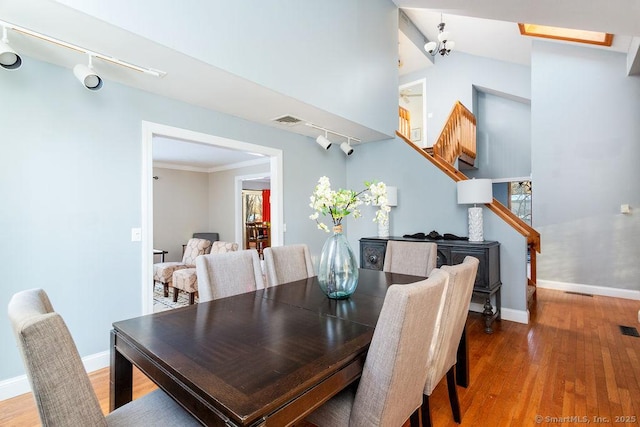 dining area with hardwood / wood-style floors, ornamental molding, and rail lighting