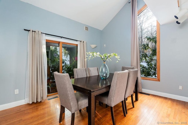 dining area featuring vaulted ceiling, plenty of natural light, and light hardwood / wood-style flooring