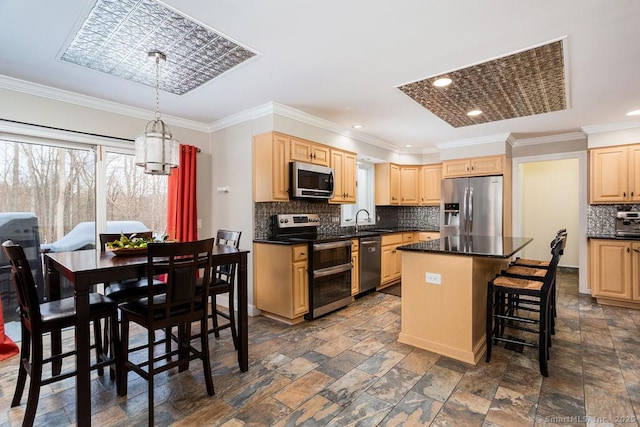 kitchen featuring a breakfast bar area, hanging light fixtures, light brown cabinets, appliances with stainless steel finishes, and a kitchen island