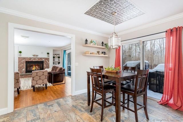 dining room with crown molding, wood-type flooring, a premium fireplace, and built in shelves