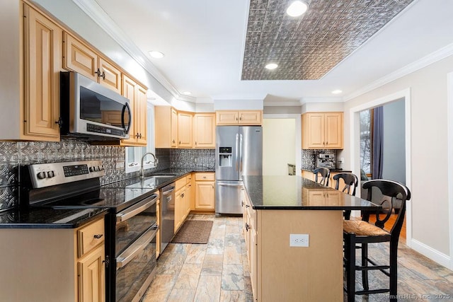 kitchen featuring sink, a breakfast bar, appliances with stainless steel finishes, a kitchen island, and light brown cabinets