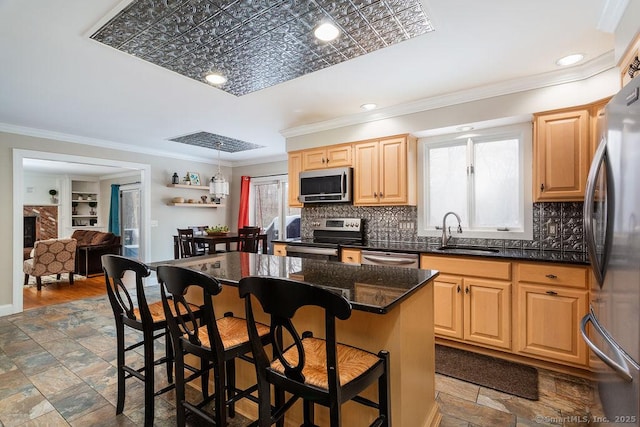 kitchen featuring sink, a center island, appliances with stainless steel finishes, a kitchen breakfast bar, and plenty of natural light