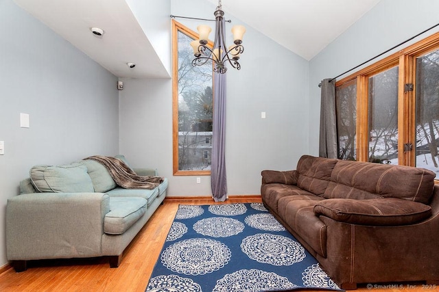 living room featuring lofted ceiling, a chandelier, and light wood-type flooring