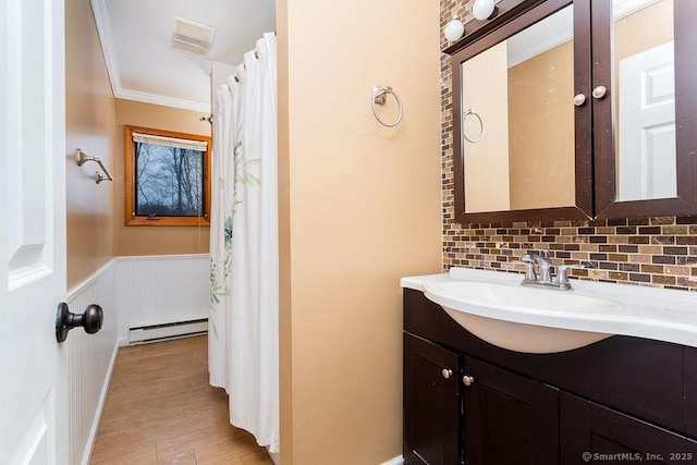 bathroom with baseboard heating, ornamental molding, vanity, hardwood / wood-style floors, and backsplash