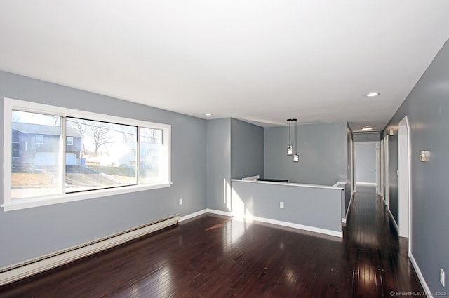 spare room featuring dark wood-type flooring and a baseboard radiator