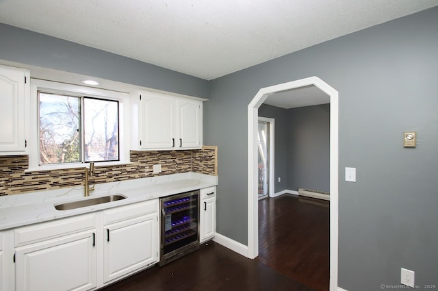 kitchen featuring white cabinetry, a baseboard radiator, sink, wine cooler, and light stone counters