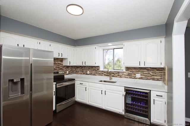 kitchen with wine cooler, white cabinetry, appliances with stainless steel finishes, and sink