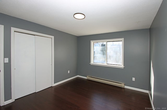 unfurnished bedroom featuring dark wood-type flooring, a baseboard radiator, and a closet