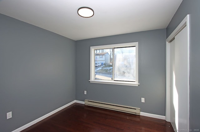 unfurnished bedroom with baseboard heating and dark wood-type flooring