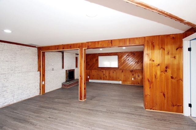 basement with baseboard heating, brick wall, wooden walls, and hardwood / wood-style floors