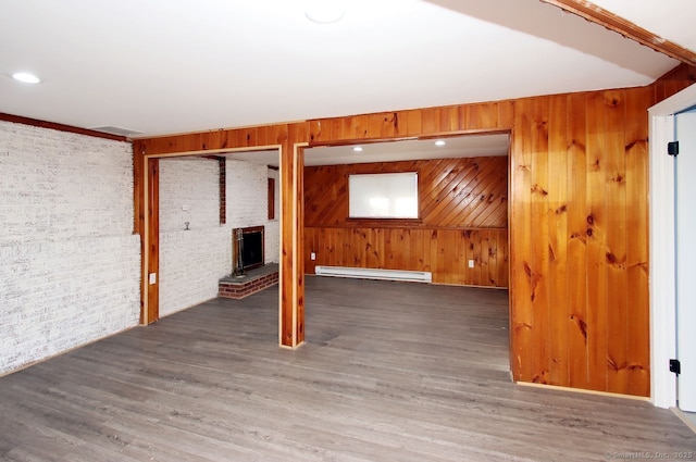 basement featuring wood walls, brick wall, wood-type flooring, and a baseboard heating unit