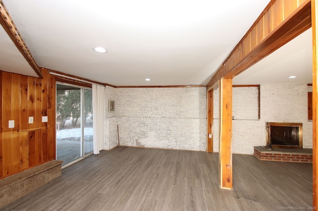 unfurnished living room with dark hardwood / wood-style flooring, brick wall, and a fireplace