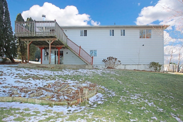 snow covered rear of property with a wooden deck and a lawn