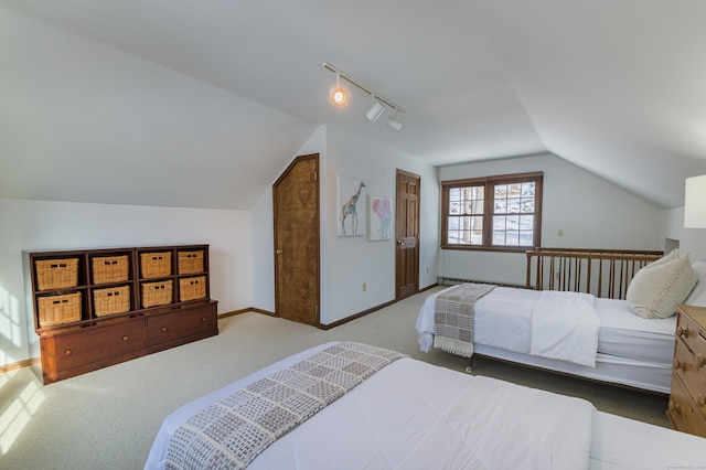 carpeted bedroom with vaulted ceiling and rail lighting