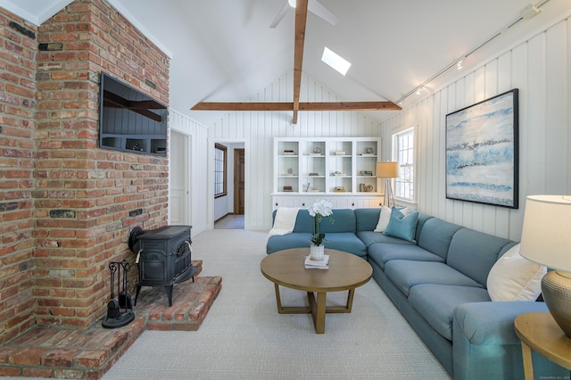 carpeted living room featuring wood walls, a skylight, high vaulted ceiling, and a wood stove