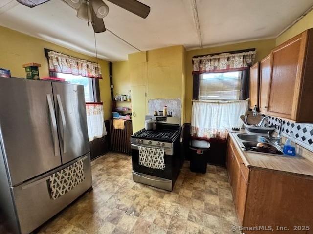 kitchen featuring stainless steel appliances, sink, ceiling fan, and decorative light fixtures