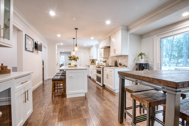 kitchen with premium range hood, white cabinets, double oven range, a center island, and a kitchen bar