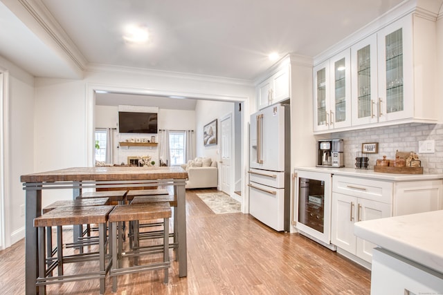 kitchen featuring wine cooler, white cabinetry, decorative backsplash, and high end white fridge