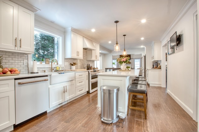 kitchen featuring white dishwasher, custom exhaust hood, white cabinets, and a sink