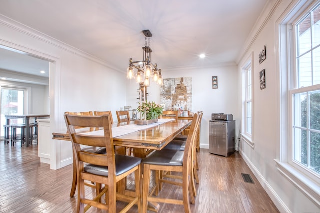 dining space featuring ornamental molding, wood finished floors, and visible vents