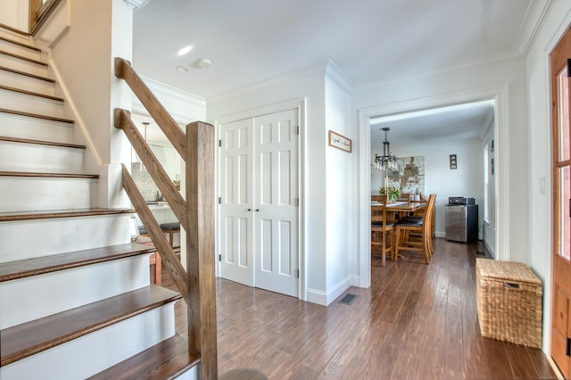 stairway featuring ornamental molding, wood finished floors, visible vents, and baseboards