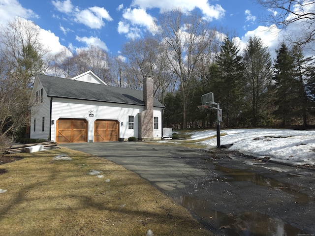 view of side of home with driveway, a garage, and a chimney