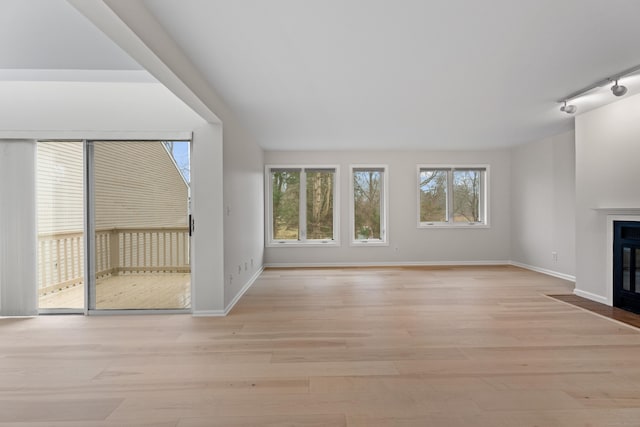 unfurnished living room featuring rail lighting and light wood-type flooring