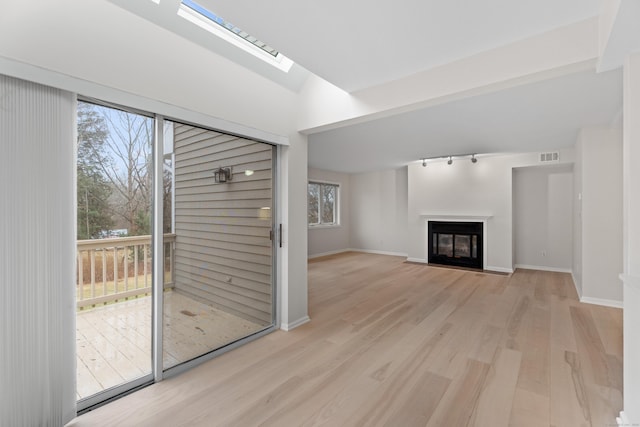 unfurnished living room with lofted ceiling with skylight and light hardwood / wood-style floors