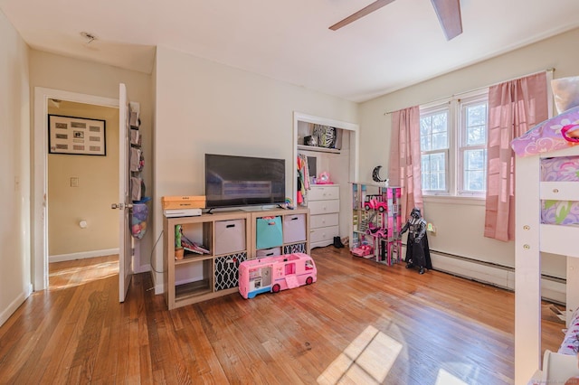 recreation room with ceiling fan, hardwood / wood-style floors, and a baseboard heating unit