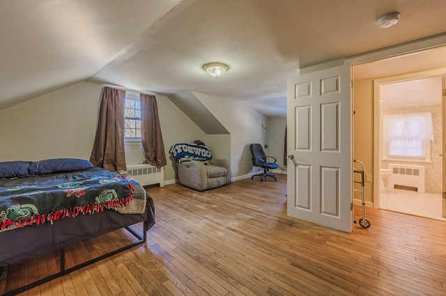 bedroom featuring ensuite bath, lofted ceiling, radiator, and hardwood / wood-style floors