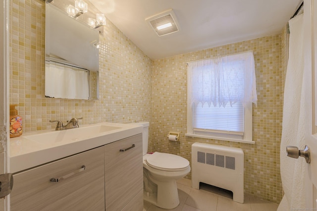 bathroom with tile patterned floors, toilet, tile walls, radiator heating unit, and vanity