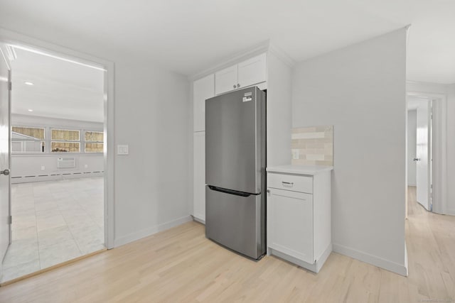 kitchen featuring stainless steel fridge, baseboard heating, white cabinetry, backsplash, and light wood-type flooring