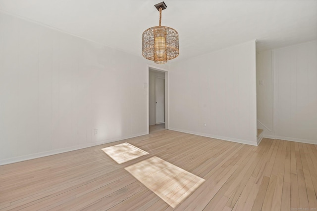 unfurnished room with light hardwood / wood-style flooring and a notable chandelier