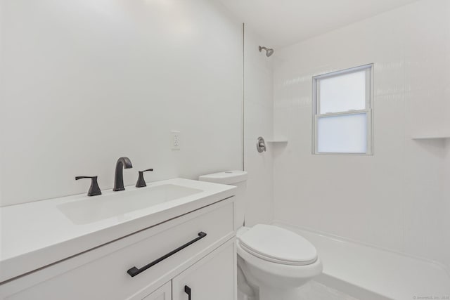 bathroom featuring vanity, toilet, and a tile shower