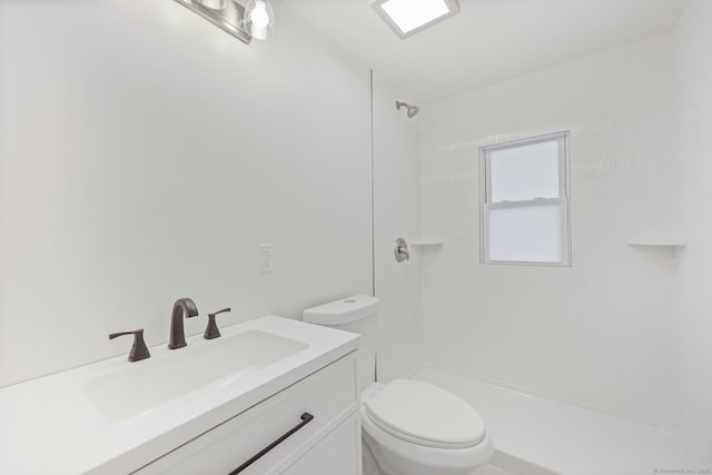 bathroom featuring vanity, tiled shower, and toilet