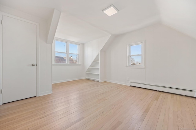 bonus room with a healthy amount of sunlight, a baseboard heating unit, and light hardwood / wood-style floors