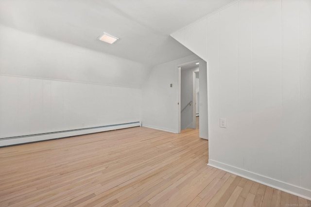 additional living space with lofted ceiling, light hardwood / wood-style flooring, and a baseboard heating unit