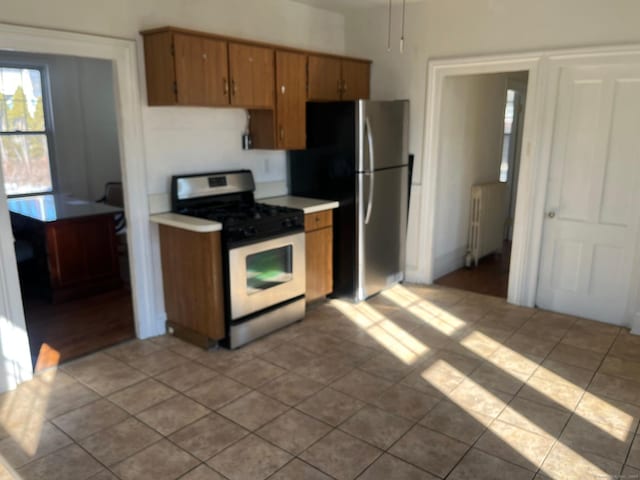 kitchen featuring light tile patterned flooring, stainless steel appliances, and radiator