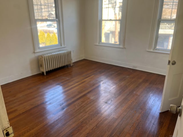 unfurnished room featuring dark wood-type flooring and radiator heating unit