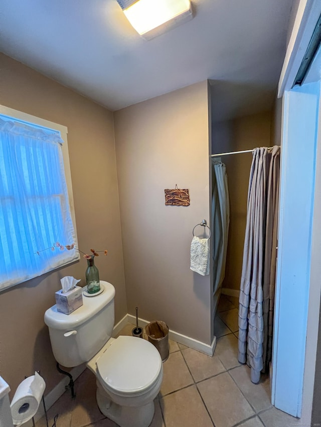 bathroom with a shower with shower curtain, tile patterned floors, and toilet