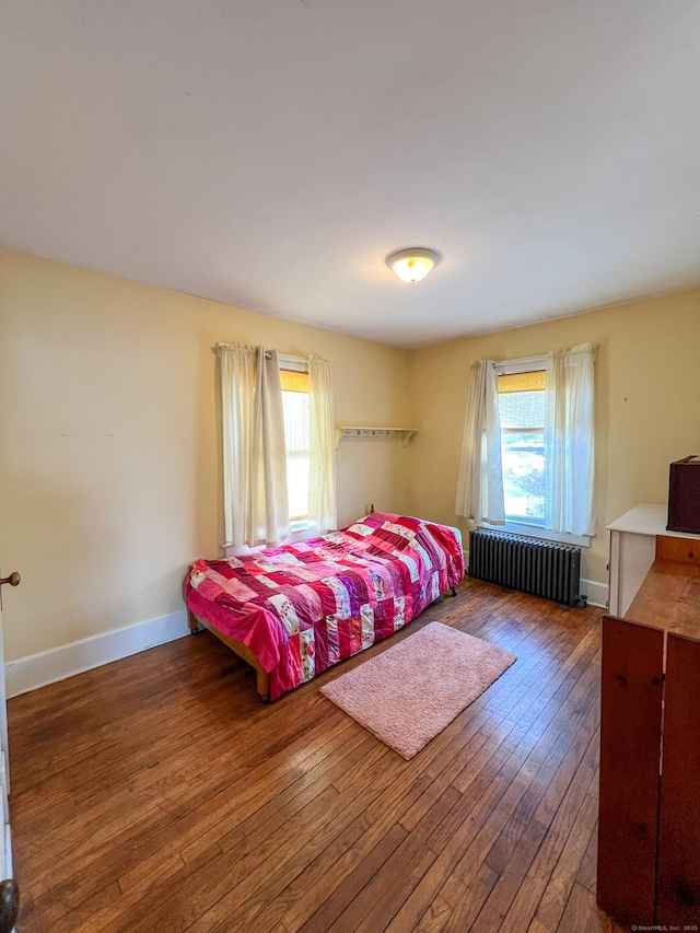 bedroom with dark hardwood / wood-style floors, radiator, and multiple windows