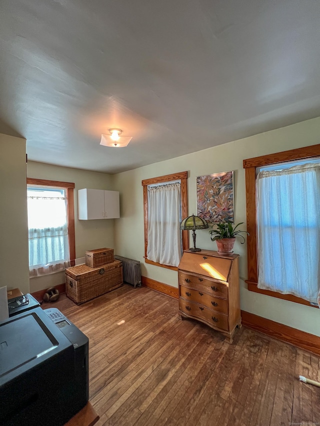 kitchen featuring hardwood / wood-style floors, radiator heating unit, and white cabinets