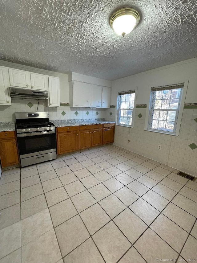 kitchen featuring white cabinetry, gas range, and light tile patterned flooring