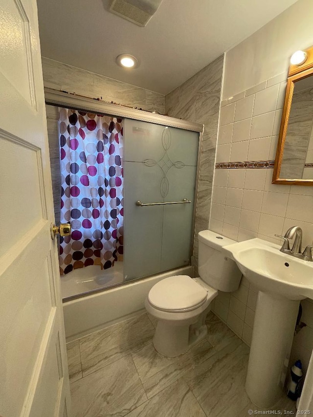 full bathroom with enclosed tub / shower combo, toilet, sink, and tile walls