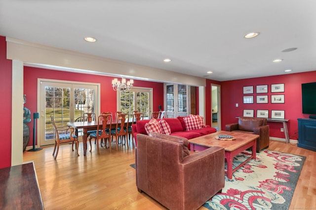 living room featuring french doors, a chandelier, and light hardwood / wood-style flooring