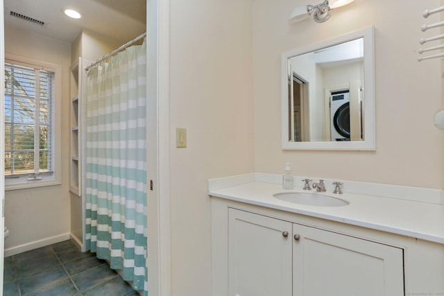 bathroom featuring tile patterned floors, vanity, and stacked washer / drying machine