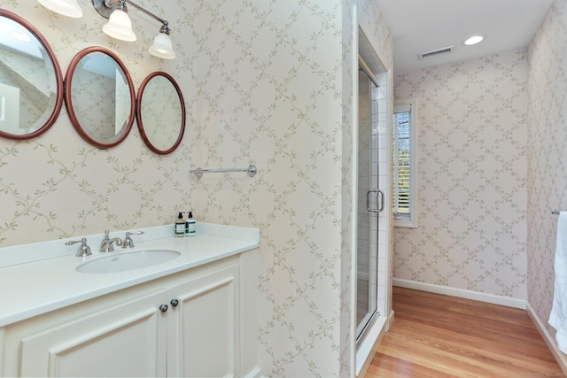 bathroom with wood-type flooring, an enclosed shower, and vanity