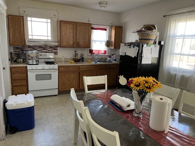 kitchen with a healthy amount of sunlight, sink, white range with gas cooktop, and black refrigerator