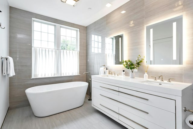 bathroom with vanity, a bathing tub, and tile walls