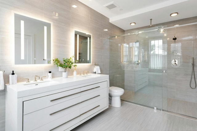 bathroom featuring toilet, a shower with shower door, tile walls, vanity, and decorative backsplash